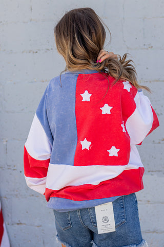 Person wearing a colorful jacket with star patterns against a gray wall