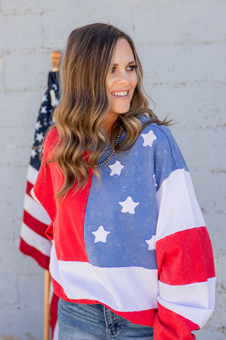 Woman wearing a flag-themed sweater with an American flag in the background