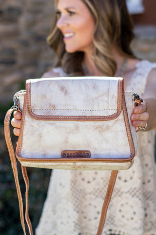 Woman holding a white handbag with brown accents outdoors