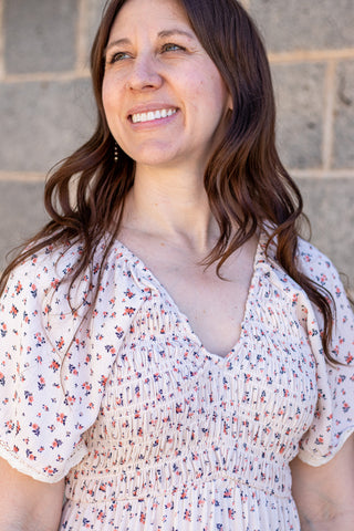 Woman in a floral dress standing in front of a stone wall