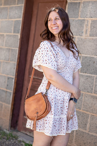 Woman in a floral dress standing in front of a stone wall