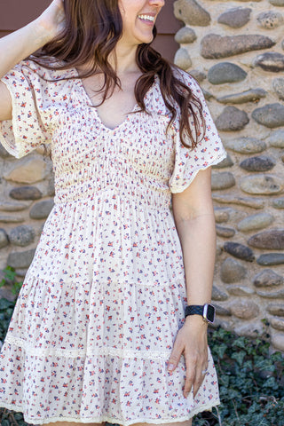 Woman in a floral dress standing in front of a stone wall