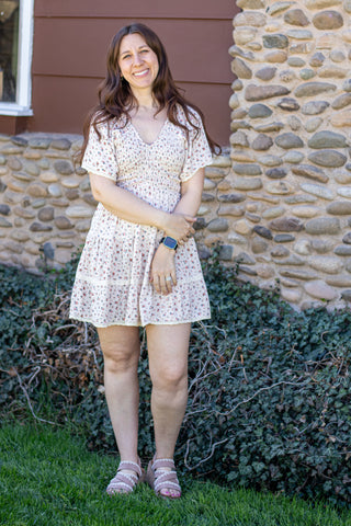 Woman in a floral dress standing in front of a stone wall
