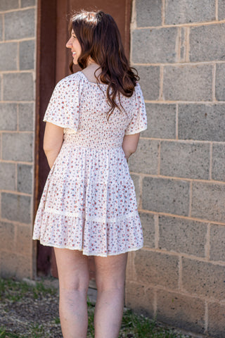 Woman in a floral dress standing in front of a stone wall