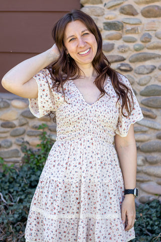 Woman in a floral dress standing in front of a stone wall