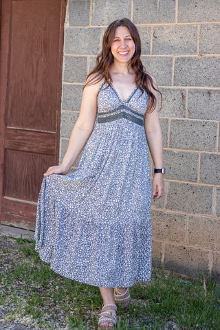 Woman wearing a floral dress standing against a brick wall