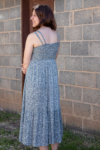 Woman wearing a floral dress standing against a brick wall