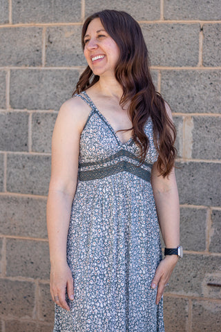 Woman wearing a floral dress standing against a brick wall