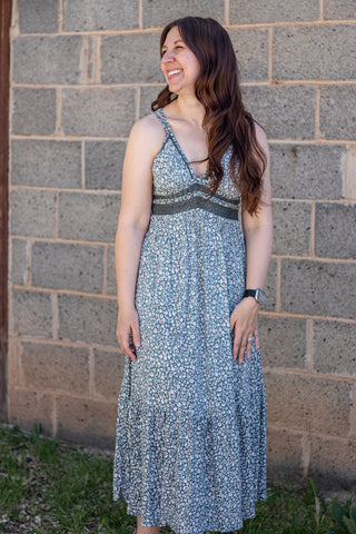 Woman wearing a floral dress standing against a brick wall