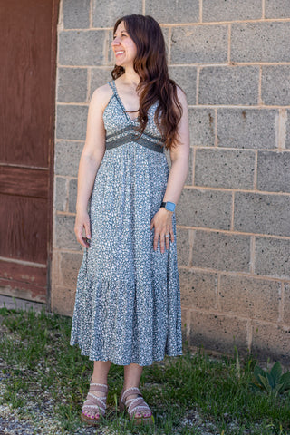 Woman wearing a floral dress standing against a brick wall