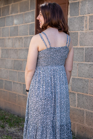 Woman wearing a floral dress standing against a brick wall