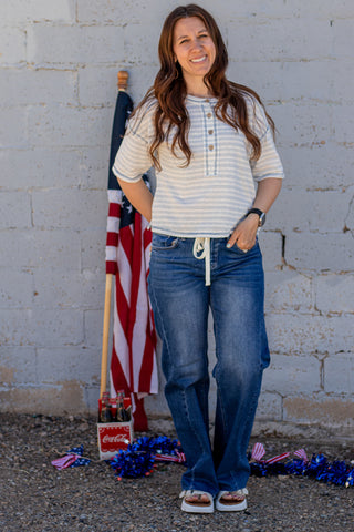 Woman standing in front of a brick wall with an American flag and decorative items on the ground.