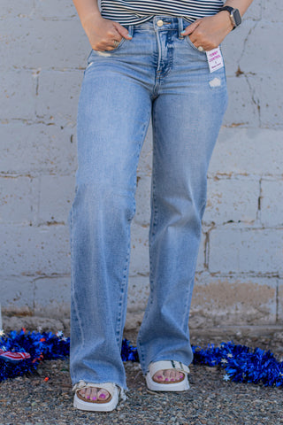 Person wearing blue jeans with a white brick wall background