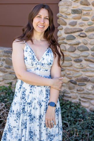 Woman wearing a floral and lace maxi dress standing in front of a stone wall.
