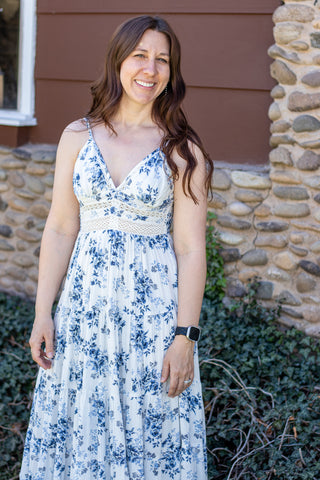 Woman wearing a floral and lace maxi dress standing in front of a stone wall.