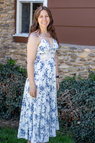 Woman wearing a floral and lace maxi dress standing in front of a stone wall.