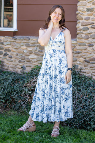 Woman wearing a floral and lace maxi dress standing in front of a stone wall.