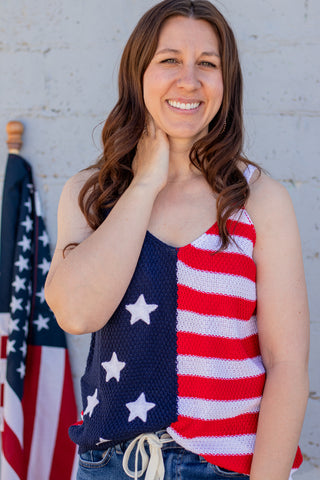 Woman wearing a tank top with an American flag design in front of a flag.